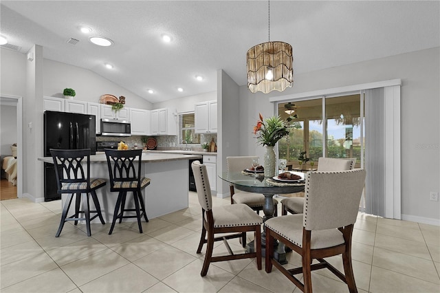 dining space with vaulted ceiling, light tile patterned floors, baseboards, and visible vents