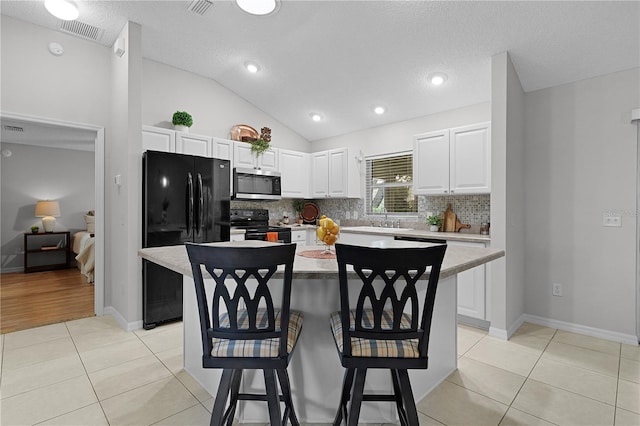 kitchen with tasteful backsplash, black appliances, light tile patterned flooring, and light countertops