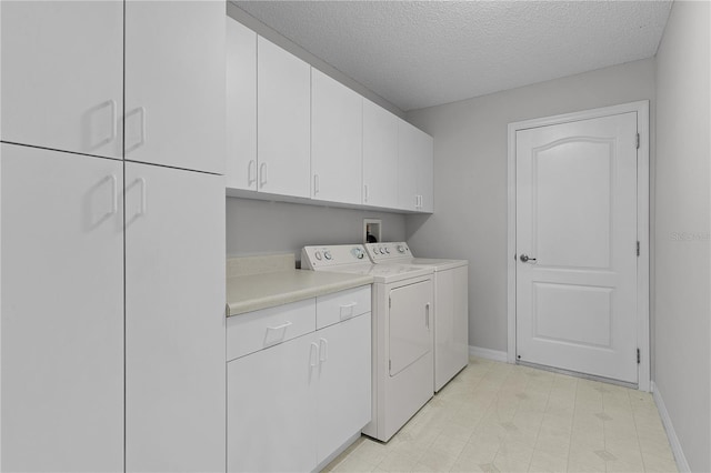 laundry area featuring cabinet space, a textured ceiling, baseboards, and separate washer and dryer