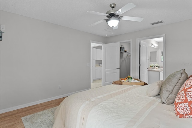 bedroom with visible vents, baseboards, a textured ceiling, and light wood-style flooring