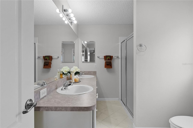 bathroom with a shower stall, a textured ceiling, toilet, and a sink