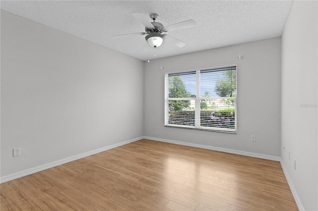 empty room with ceiling fan, light wood-style flooring, baseboards, and a textured ceiling