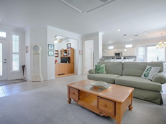 living room featuring light carpet, ornate columns, ornamental molding, and ceiling fan with notable chandelier