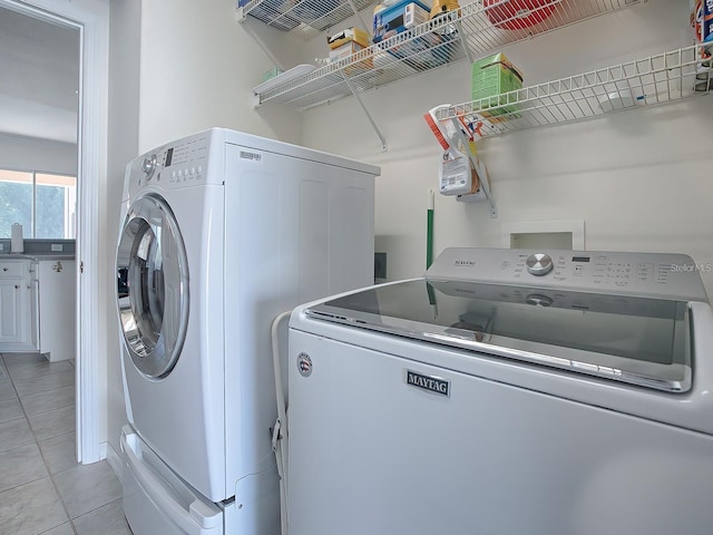 clothes washing area featuring washer and dryer and light tile patterned flooring