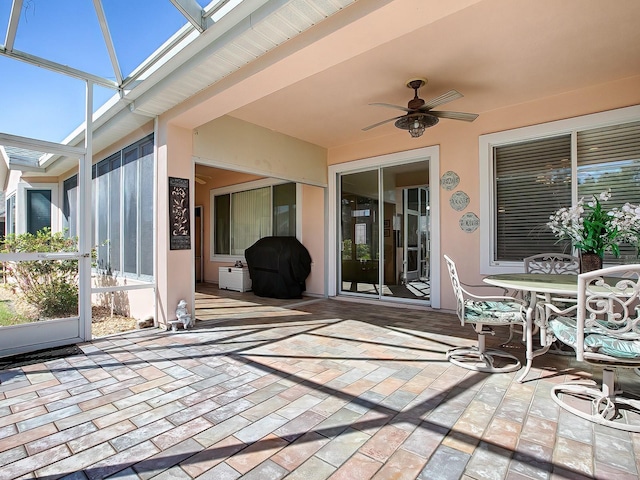 view of patio with grilling area, glass enclosure, and ceiling fan