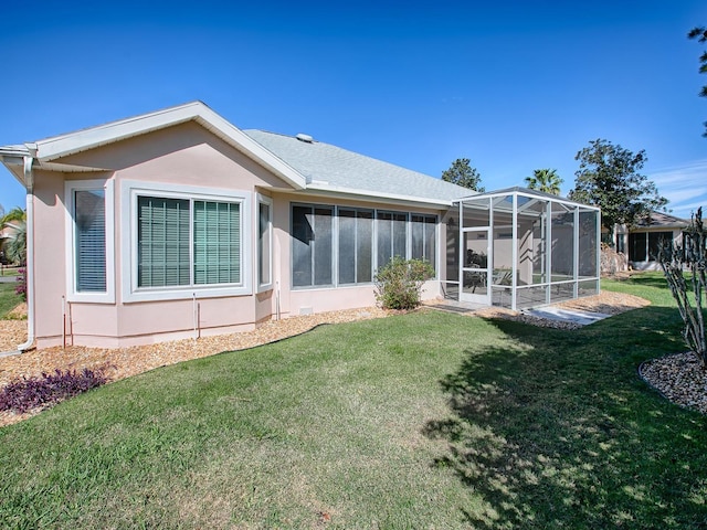 rear view of house with a yard, glass enclosure, and a sunroom