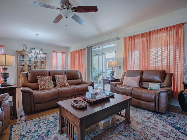 living room with wood-type flooring and ceiling fan with notable chandelier