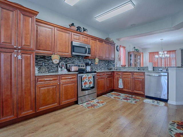 kitchen with pendant lighting, stainless steel appliances, a chandelier, and light wood-type flooring