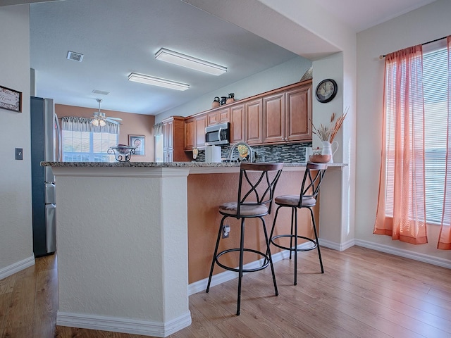 kitchen featuring ceiling fan, a healthy amount of sunlight, light hardwood / wood-style flooring, and stainless steel appliances