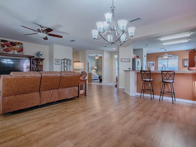 living room featuring sink, ceiling fan with notable chandelier, and light hardwood / wood-style floors