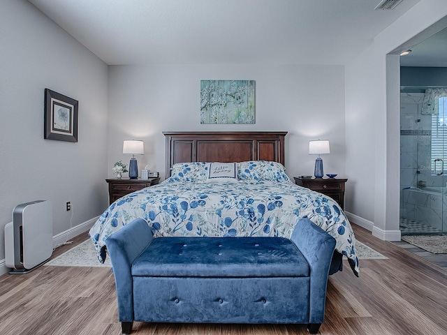 bedroom featuring ensuite bath and wood-type flooring