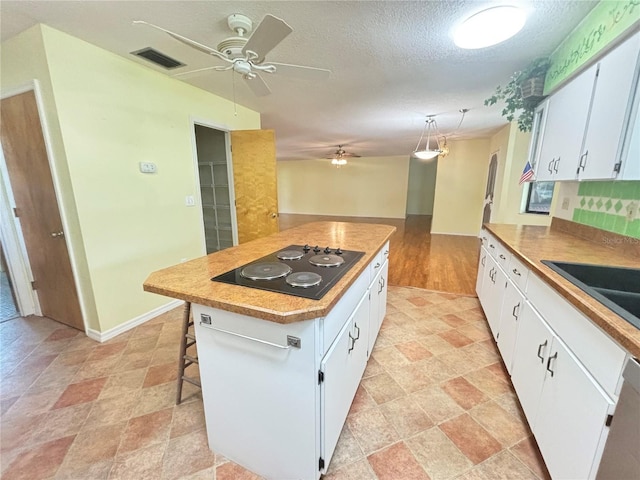 kitchen featuring black electric cooktop, white cabinets, a center island, and pendant lighting