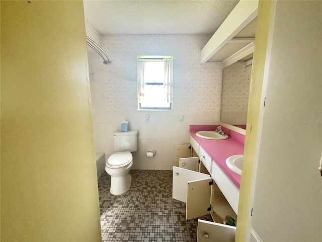 full bathroom with washtub / shower combination, a textured ceiling, toilet, tile walls, and vanity