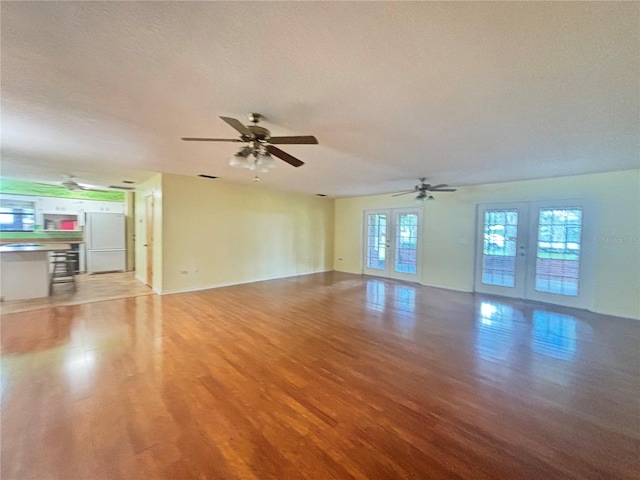 unfurnished living room featuring french doors, a textured ceiling, light wood-type flooring, and ceiling fan