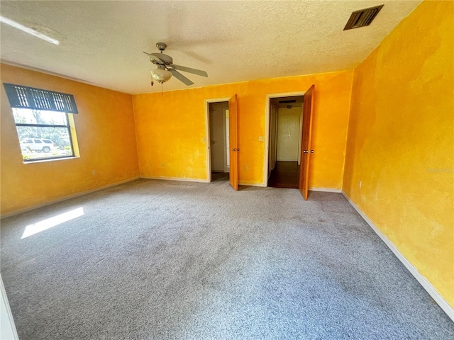 carpeted spare room with a textured ceiling and ceiling fan