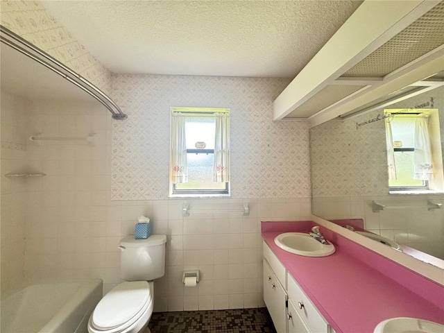 full bathroom with toilet, a textured ceiling, vanity, and tile walls