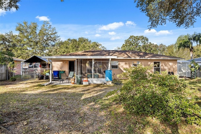 back of property featuring a carport, a patio area, and a sunroom