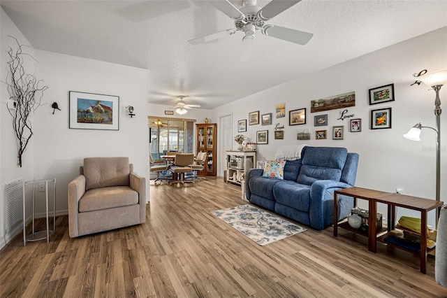 living room featuring hardwood / wood-style floors, ceiling fan, and a textured ceiling