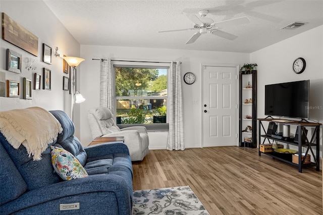 living room with a textured ceiling, light hardwood / wood-style flooring, and ceiling fan