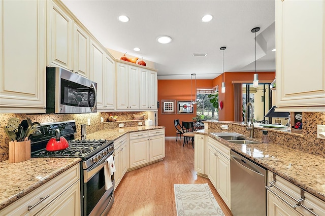 kitchen featuring light stone counters, sink, pendant lighting, light hardwood / wood-style floors, and stainless steel appliances