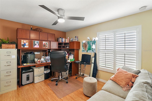 office with light hardwood / wood-style floors, a healthy amount of sunlight, and ceiling fan