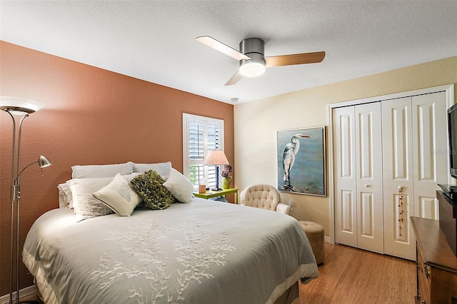 bedroom featuring light hardwood / wood-style flooring, a textured ceiling, a closet, and ceiling fan