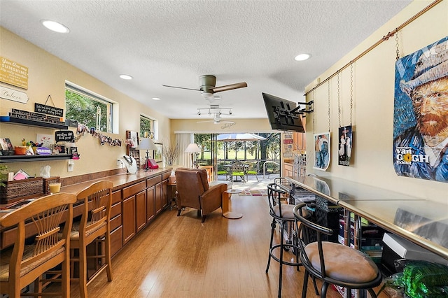 interior space featuring a textured ceiling, light wood-type flooring, and ceiling fan