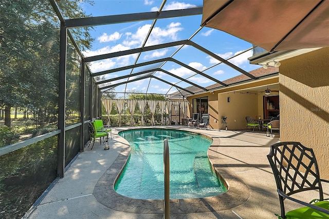 view of swimming pool featuring a patio area, glass enclosure, and ceiling fan