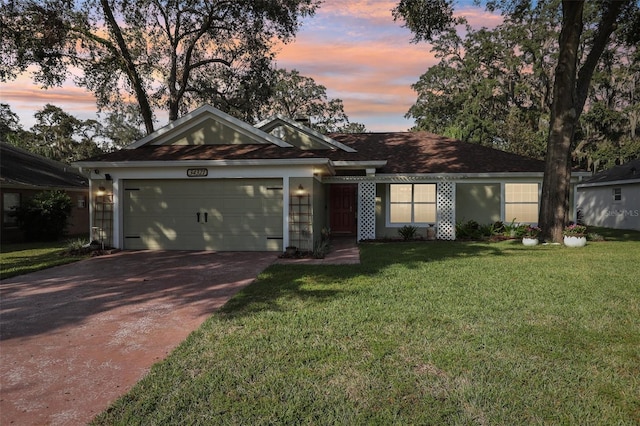 ranch-style home featuring a garage and a lawn