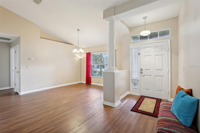 entryway featuring dark hardwood / wood-style flooring, lofted ceiling, ornate columns, and a chandelier