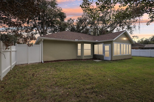 back house at dusk featuring a yard