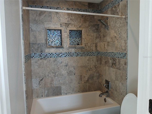 bathroom with toilet and tiled shower / bath combo