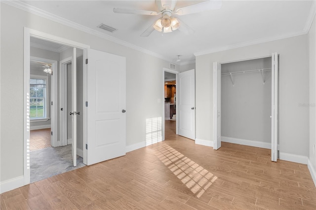 unfurnished bedroom with crown molding, a closet, light wood-type flooring, and ceiling fan