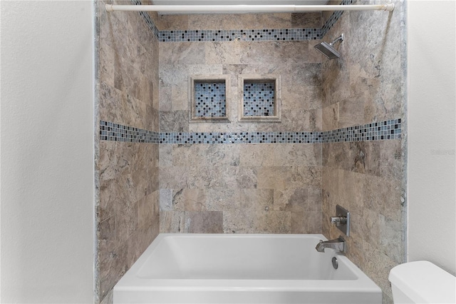 bathroom featuring toilet and tiled shower / bath