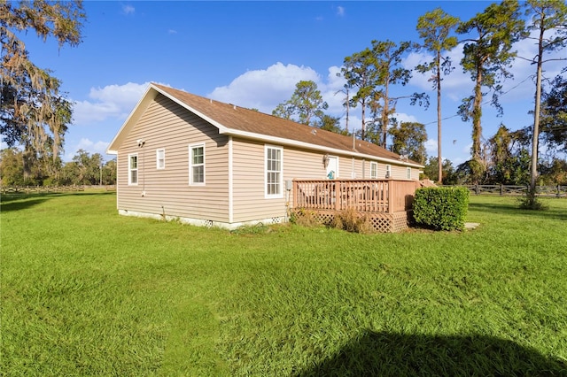 rear view of property featuring a wooden deck and a lawn