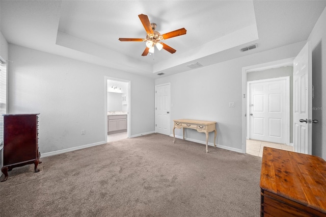 unfurnished bedroom with ceiling fan, a raised ceiling, carpet flooring, and ensuite bathroom