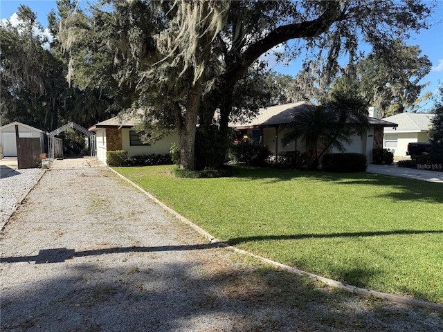 ranch-style house featuring a storage unit and a front lawn