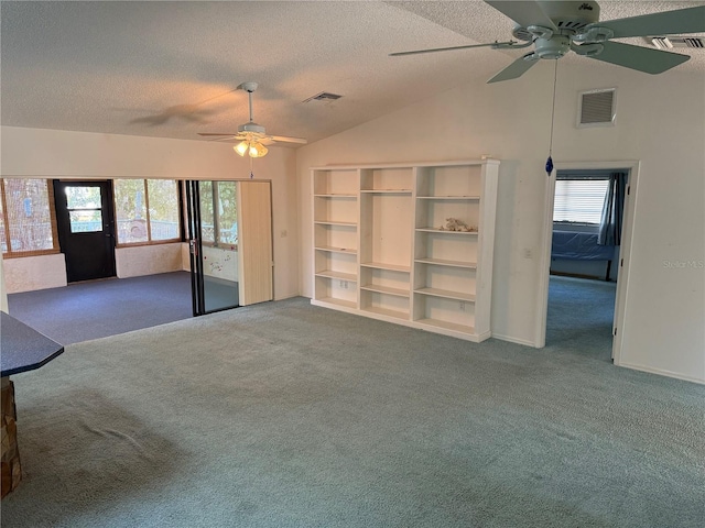 unfurnished living room featuring vaulted ceiling, a textured ceiling, carpet floors, and plenty of natural light