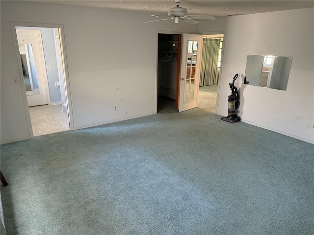 carpeted empty room with ceiling fan and a textured ceiling