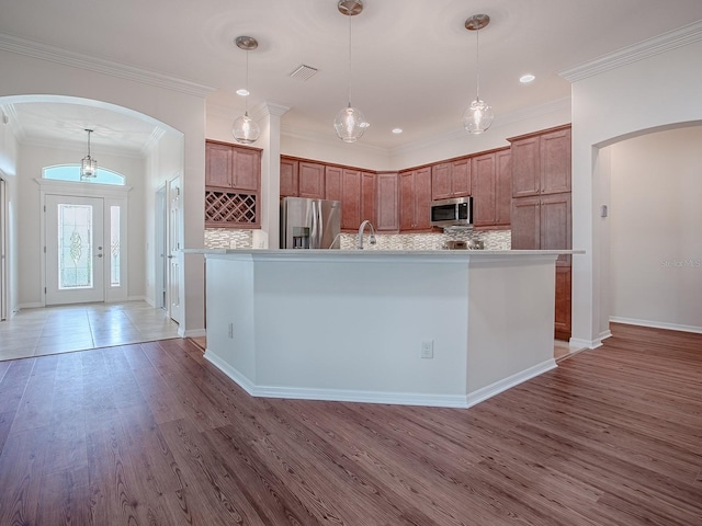 kitchen featuring decorative backsplash, a center island with sink, stainless steel appliances, and wood-type flooring