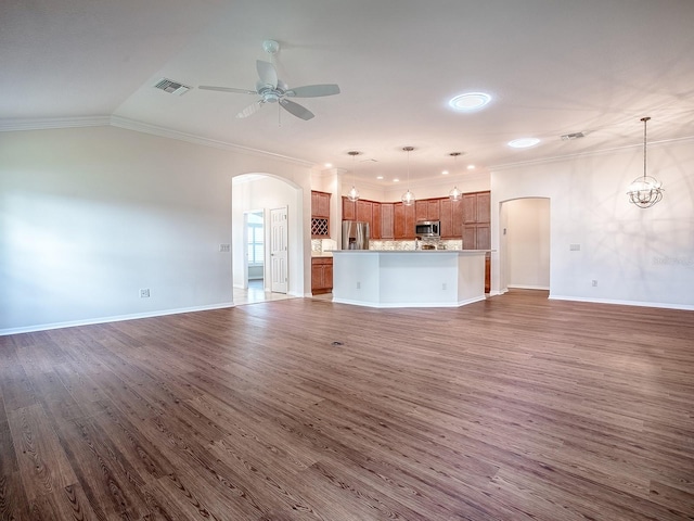 unfurnished living room with lofted ceiling, dark wood-type flooring, crown molding, and ceiling fan with notable chandelier