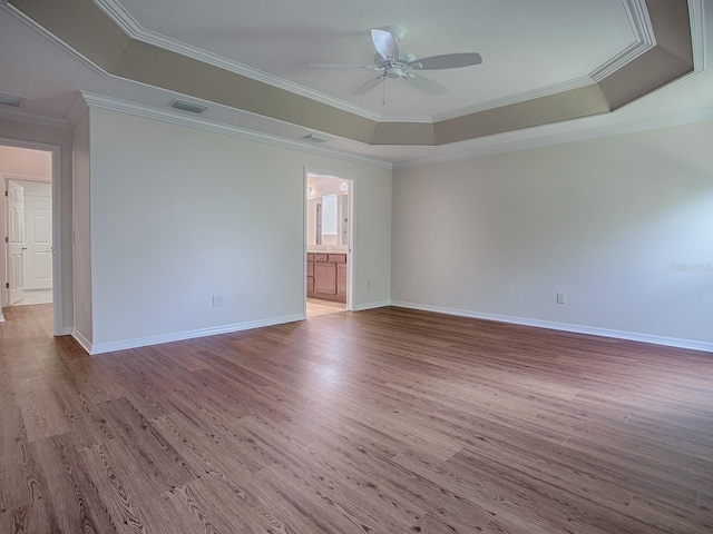 unfurnished room featuring crown molding, a tray ceiling, light hardwood / wood-style floors, and ceiling fan