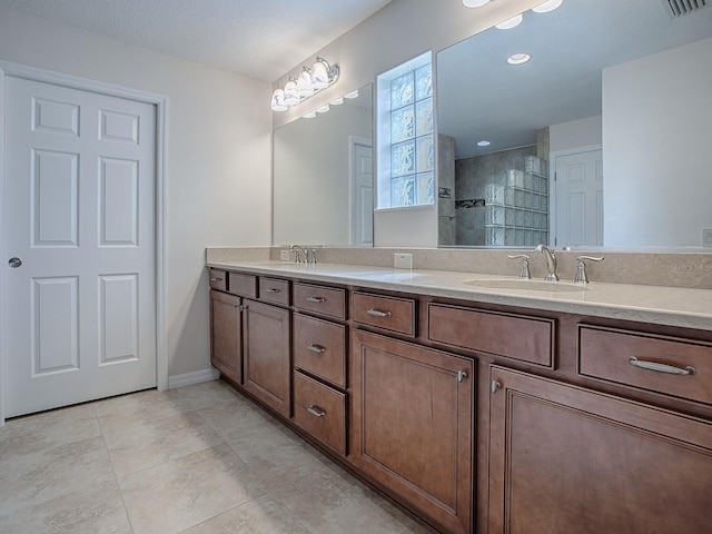 bathroom with vanity, a tile shower, a textured ceiling, and tile patterned floors