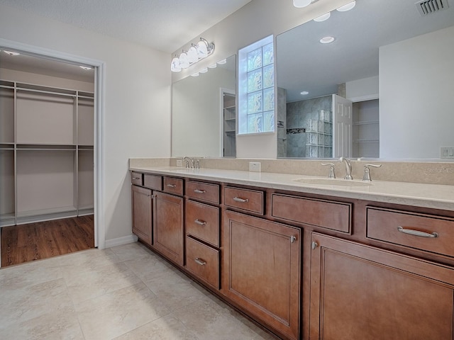 bathroom featuring vanity, a tile shower, and tile patterned floors