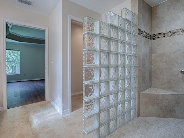 bathroom with hardwood / wood-style flooring, ornamental molding, and tiled shower