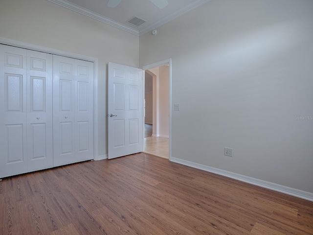 unfurnished bedroom featuring a closet, light hardwood / wood-style floors, crown molding, and ceiling fan