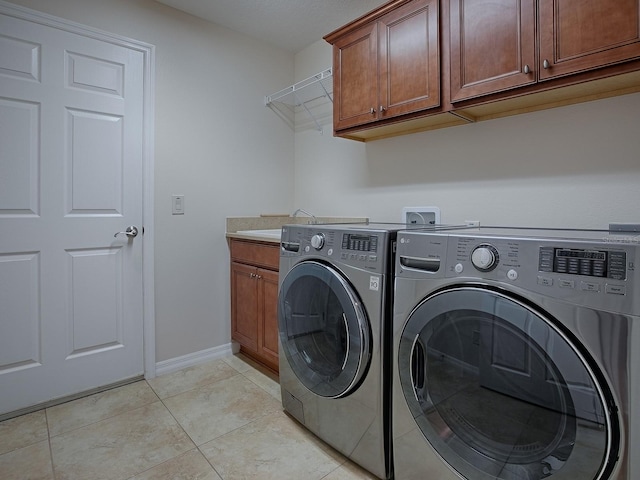 washroom with sink, independent washer and dryer, light tile patterned floors, and cabinets