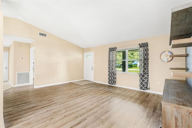 unfurnished living room featuring vaulted ceiling and hardwood / wood-style flooring