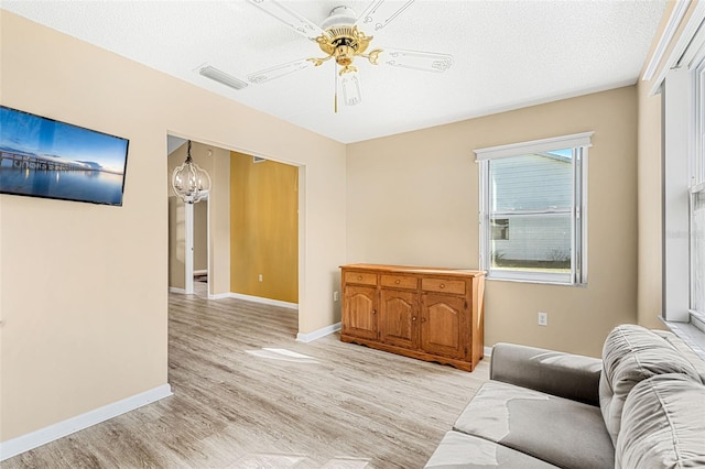 living room featuring light hardwood / wood-style flooring, a textured ceiling, and ceiling fan