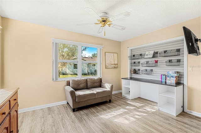 living area featuring light hardwood / wood-style floors, a textured ceiling, and ceiling fan